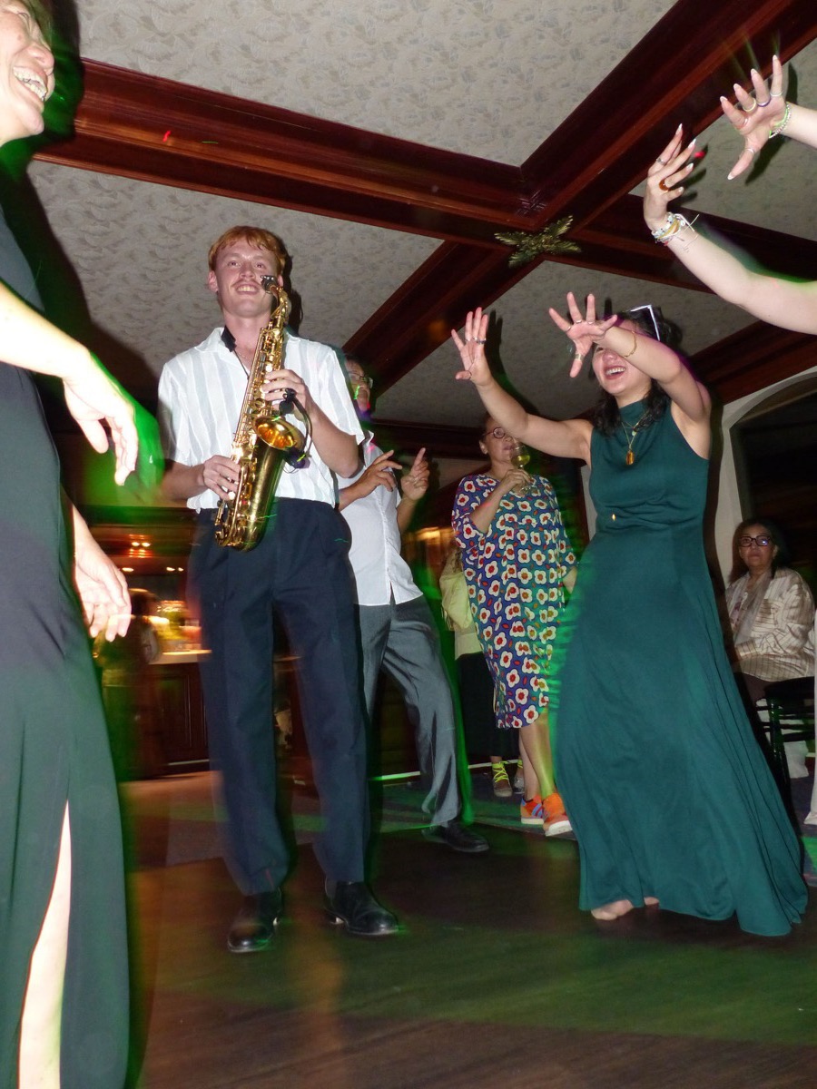 Invités dansant autour du saxophoniste lors d'une soirée corporate